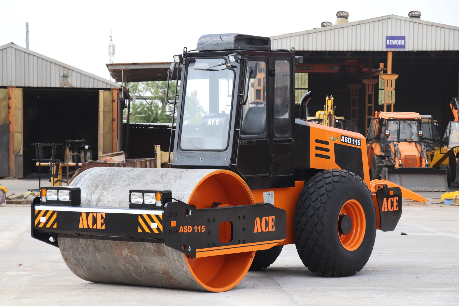 Orange single-drum road roller parked in an equipment yard.