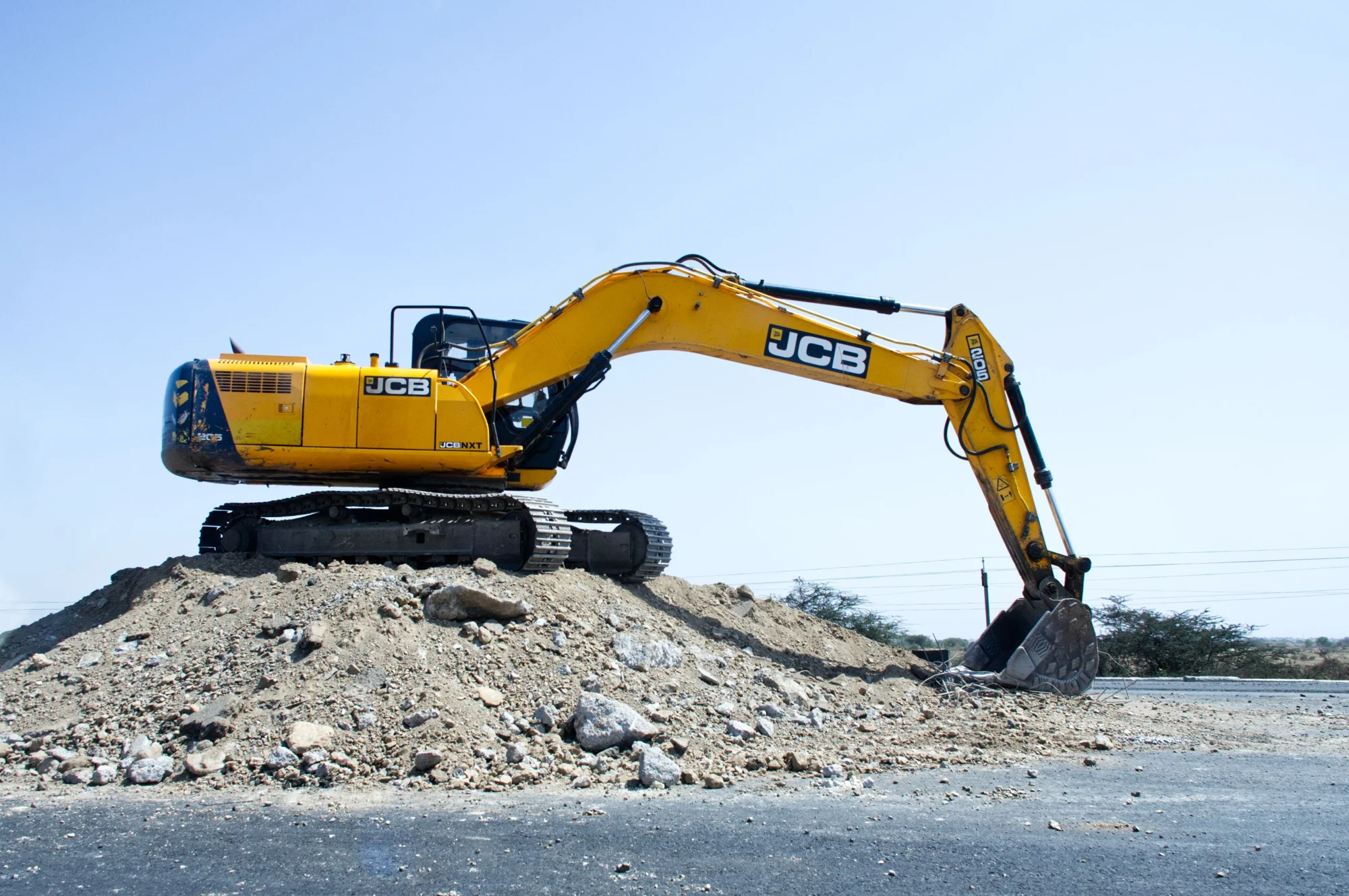 Yellow excavator on open ground at a construction site in bright natural daylight.